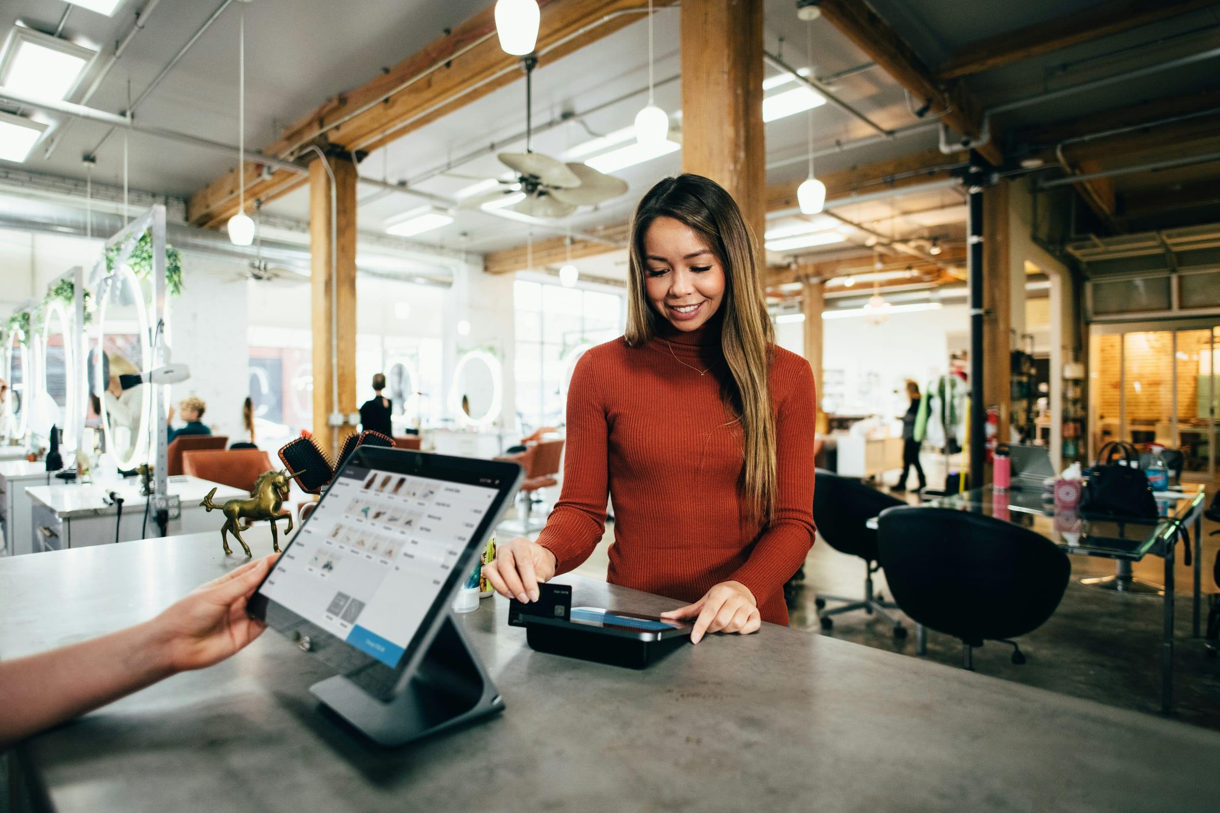 A shop assistant taking a card payment at the counter.
